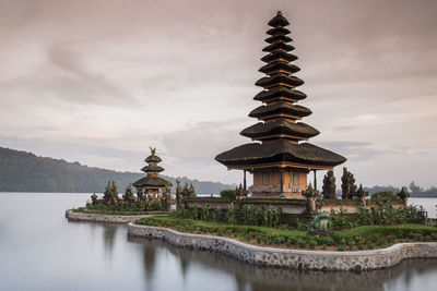 Traditional building by lake against sky