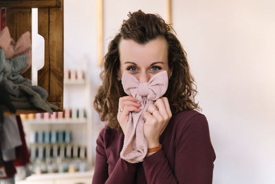 A playful moment captured as a fashion designer covers her nose with a handmade textile bow
