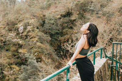 Young woman standing by railing