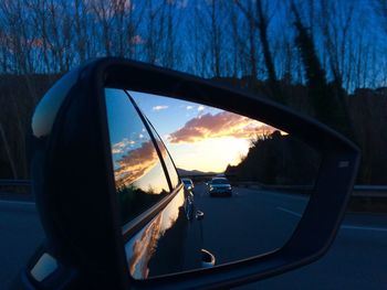 Reflection of clouds in side-view mirror of car