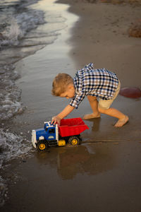 Boy playing with toy car on beach