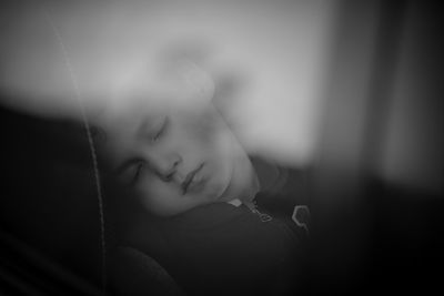 Close-up of cute boy sleeping in car seen through window