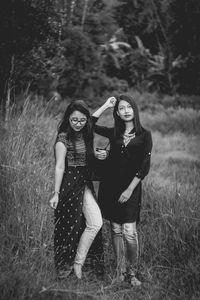 Young women standing on grass against trees