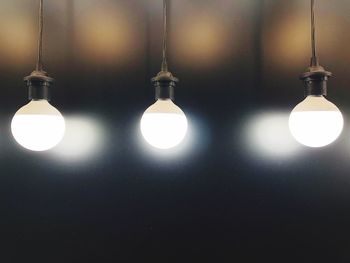 Close-up of illuminated light bulb against wall at night