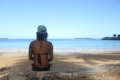 Rear view of woman on beach against clear sky