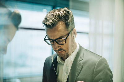 Thoughtful male professional wearing eyeglasses and headphones in office