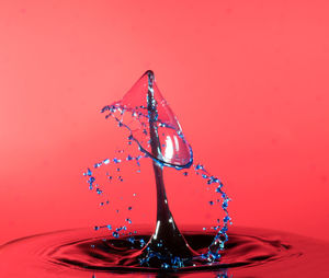 Close-up of water splashing against red background