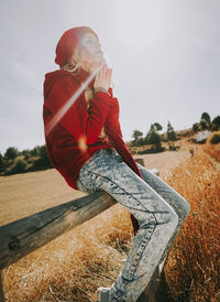 Side view of woman standing on field against sky