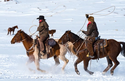 People riding horses on snowy land