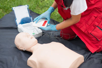 Midsection of paramedic practicing cpr on dummy