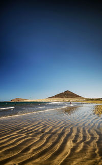 Scenic view of beach against clear blue sky