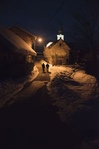 People on street amidst illuminated buildings in city at night