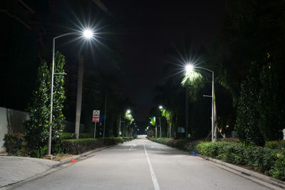 Empty road along trees at night