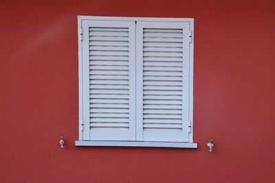 Close-up of closed window on red wall