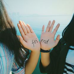 Cropped image of friends with text on hand against sky