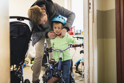 Father wearing cycling helmet to son at home