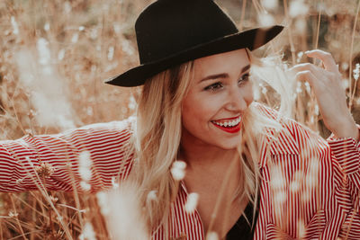 Close-up of young woman wearing hat on field during sunset