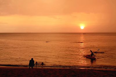 Silhouette people on beach against sky during sunset