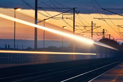 Railway at dawn. light trails of passenger train at railroad station.