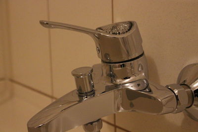 Close-up of water faucet against wall at home