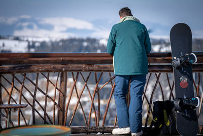 Rear view of man standing by railing woth a mountain view