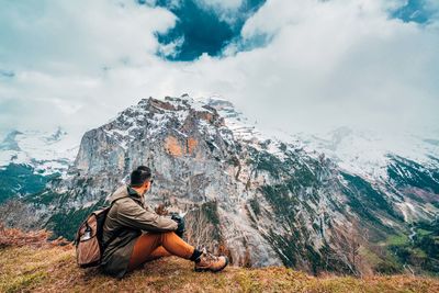 Man sitting on rock against mountain