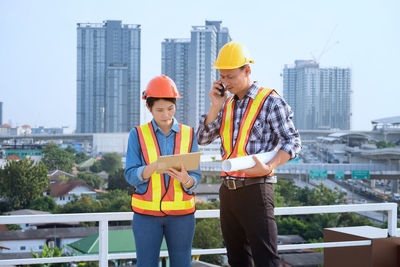 Engineers using technologies while standing against buildings in city