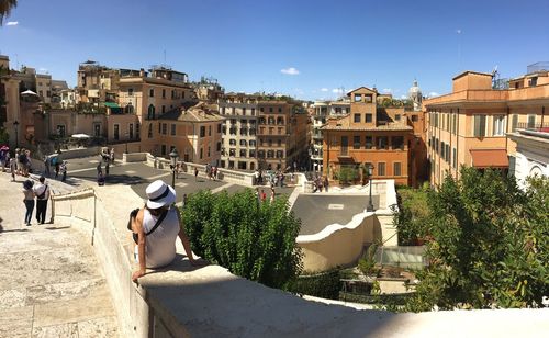 People at observation point in city against blue sky