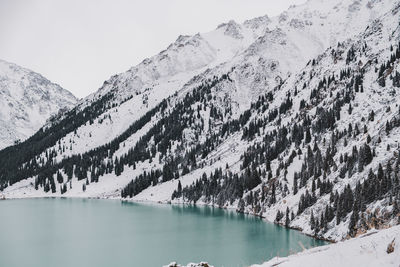 Scenic view of lake by snowcapped mountains against sky