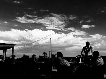 People on landscape against cloudy sky