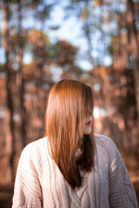 Woman with long hair standing against tree