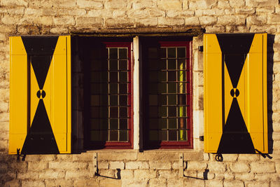 Yellow closed windows on wall of building