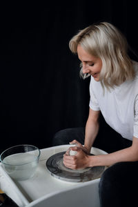 Girl sitting behind pottery wheel and laughing