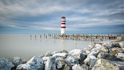 Lighthouse by sea against sky