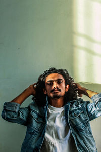 Portrait of young man looking away against wall