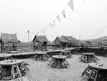 Chairs on table by buildings against clear sky