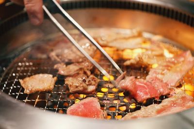 Close-up of person preparing food on barbecue grill