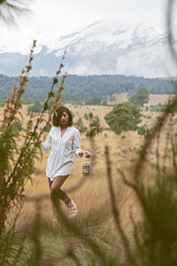 Beautiful woman walking with lantern on grassy field