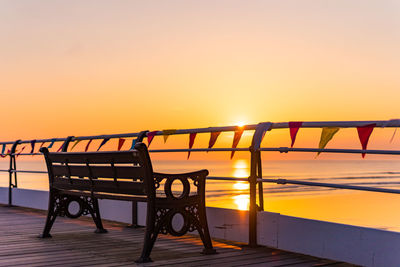 Empty chairs and table against orange sky