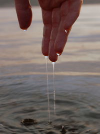 Close-up of hand pouring water in sea