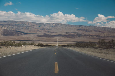 Road by desert against sky