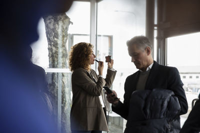 Side view of businesswoman applying lipstick before seminar at conference center