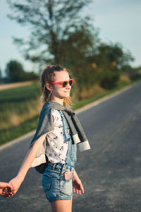 Young woman wearing sunglasses standing on road