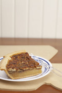 Two slices of pecan pie on a serving plate on a louisiana-shaped piece of plywood