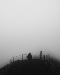 Rear view of silhouette people walking on bridge against sky