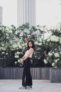 Portrait of woman standing against plants in city