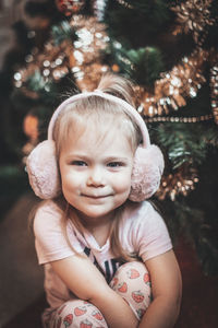 Portrait of cute girl sitting by christmas tree