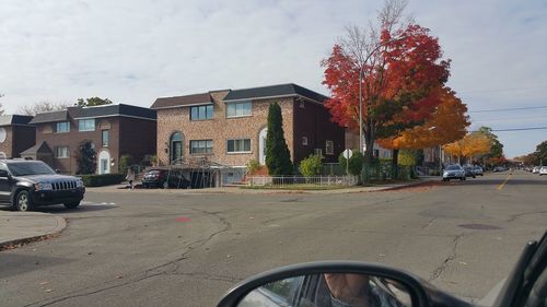 Cars on road by buildings against sky