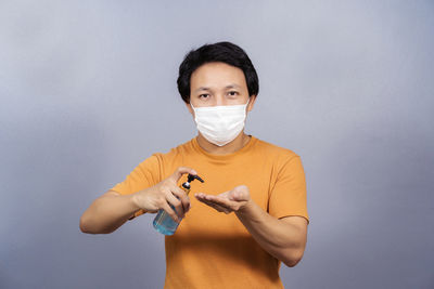 Portrait of young man holding camera against white background