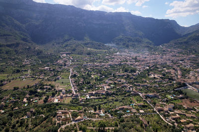 Aerial view of agricultural field by buildings against sky